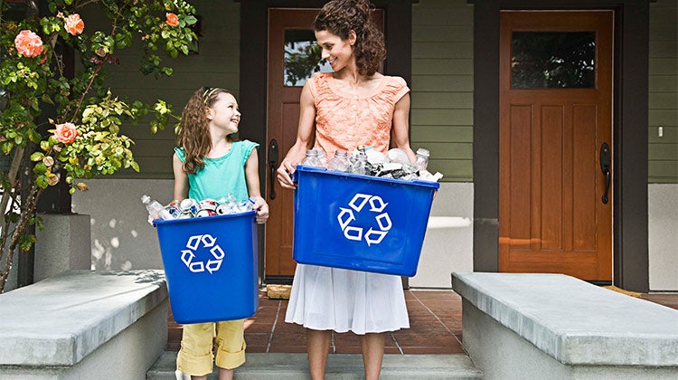 Mother and daughter holding recycling bins