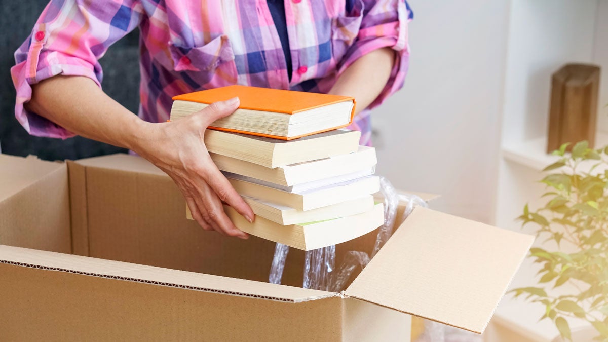 Person putting books in a packing box