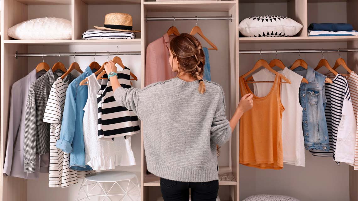 Women organizing her closet with clothes in it