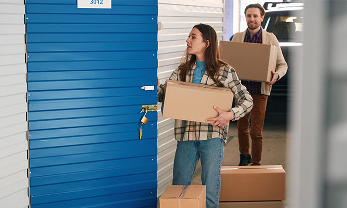 A man and woman packing boxes into a storage locker. 