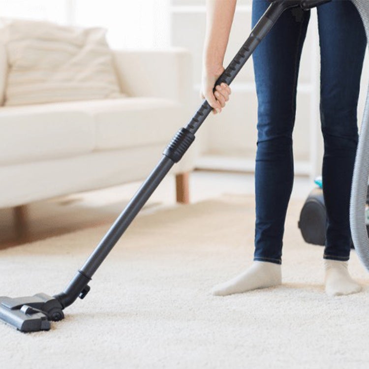 Woman vacuuming white carpet 