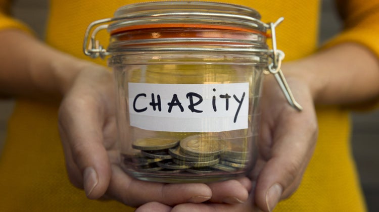 Person holding charity jar with coins Person holding charity jar with coins