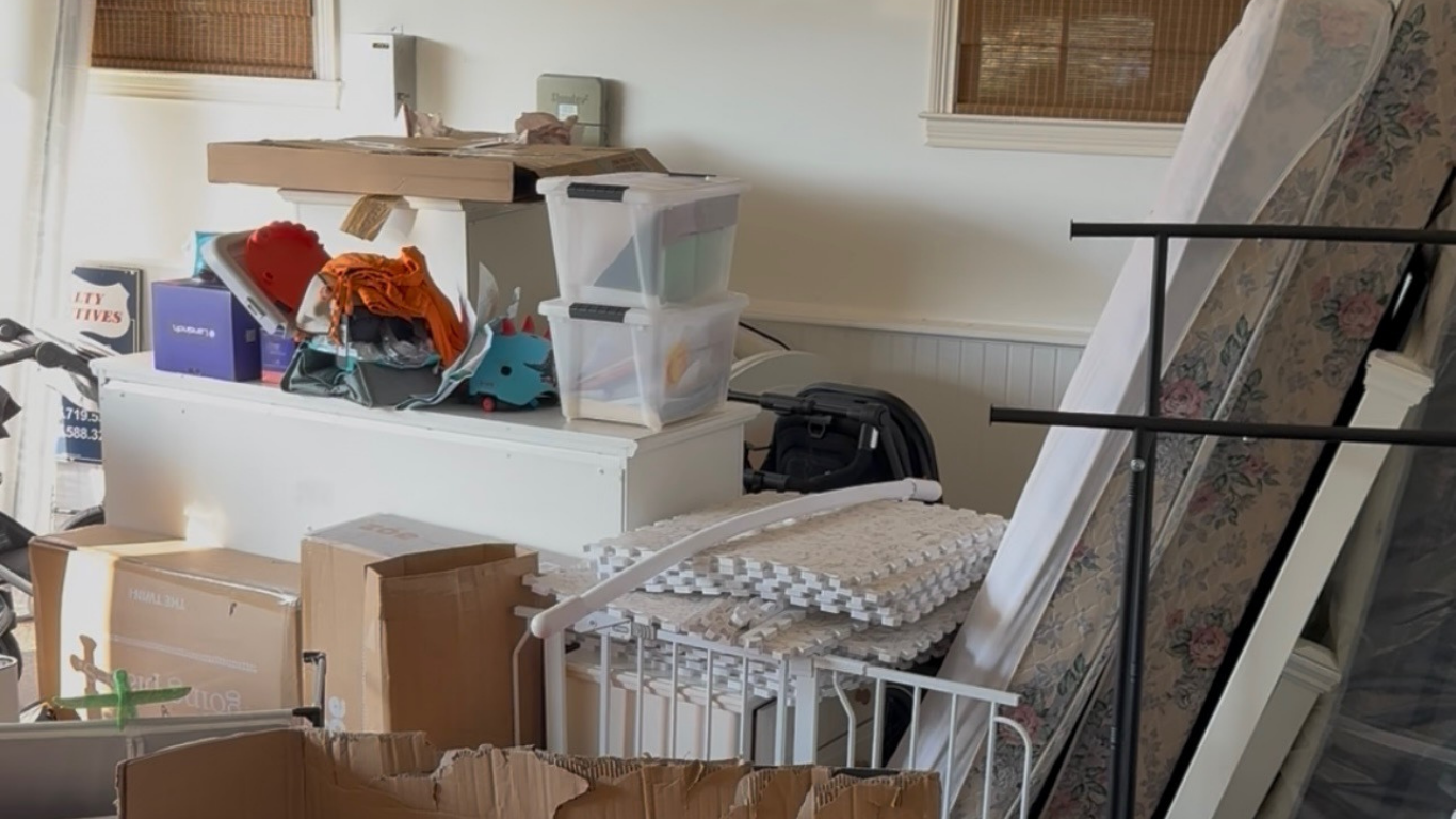 Moving boxes, old furniture, and random clutter in a garage Moving boxes, old furniture, and random clutter in a garage