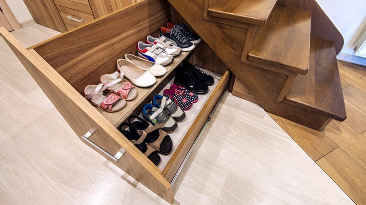 Shoe storage rack under brown wooden stairs