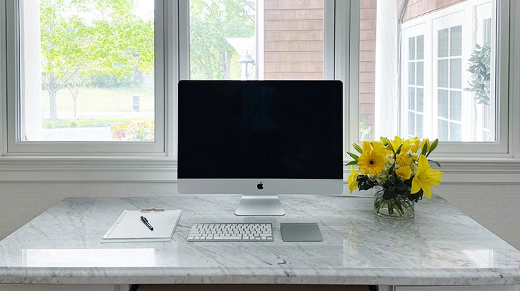 home office desktop with notepad and yellow flowers