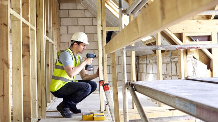 Construction worker drilling wooden planks together