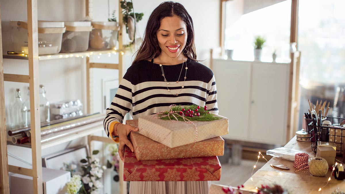 Woman holding stack of presents in a white room