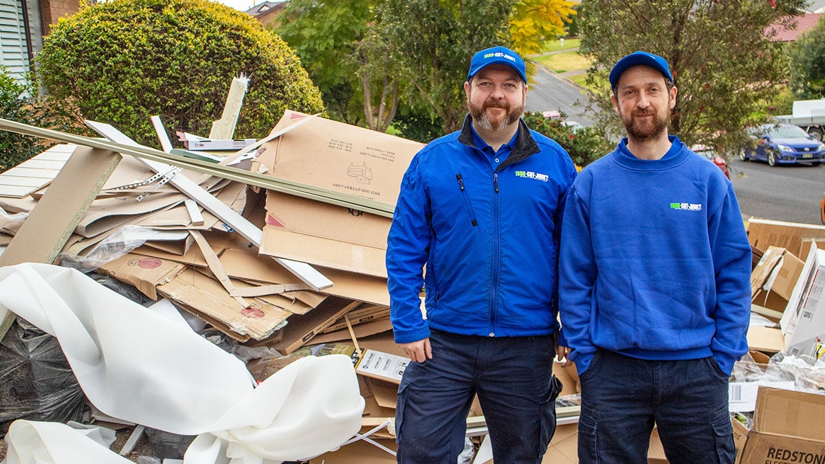 Two 1-800-GOT-JUNK? team members in front of a construction debris pile