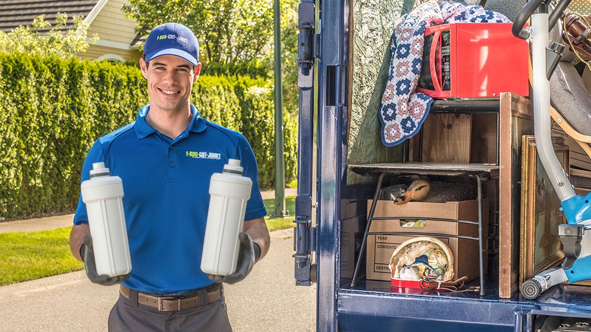 1-800-GOT-JUNK? truck team member holding a refrigerator water filter.