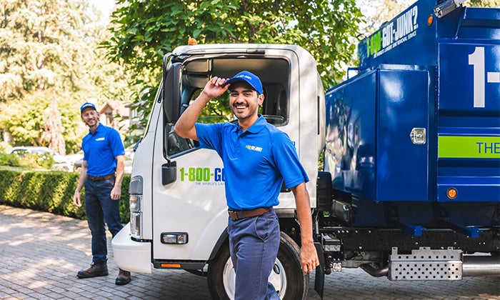 Two 1-800-GOT-JUNK? Truck Team Members smiling in front of the truck