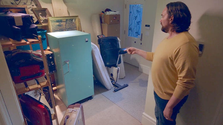 Man in a yellow sweater pointing at an old blue fridge to make it disappear