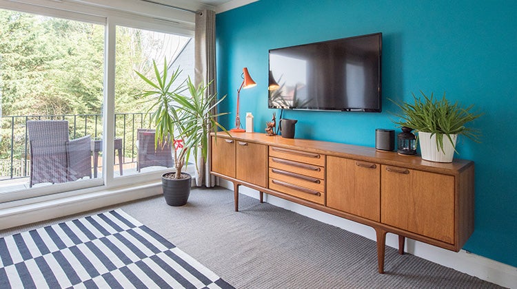 Image of a bedroom with a mounted wall TV on a bright blue wall