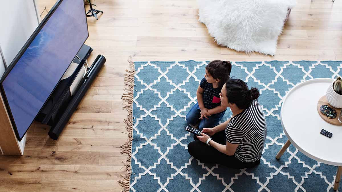 A mother and son sitting on the floor watching television