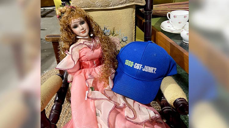 Sleeping beauty doll sitting next to a 1-800-GOT-JUNK? hat
