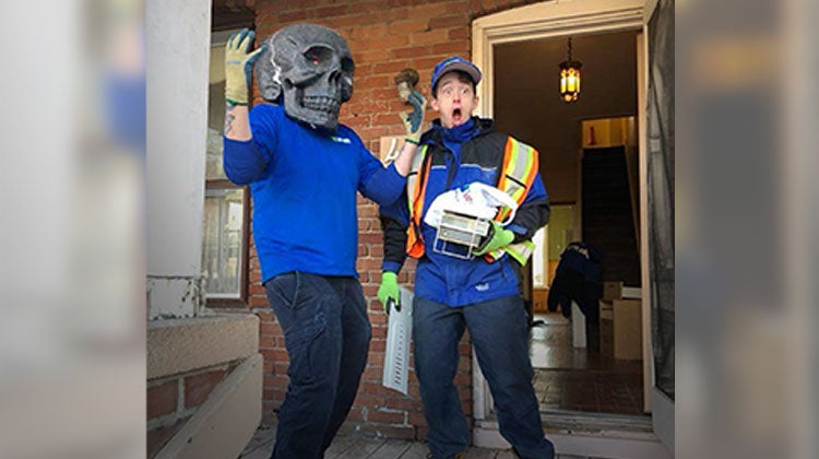 One 1-800-GOT-JUNK? team member looking shocked while the other team member wears a skull mask