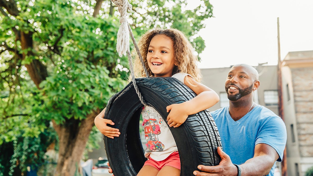 A father and daughter playing on a swing made from old tire