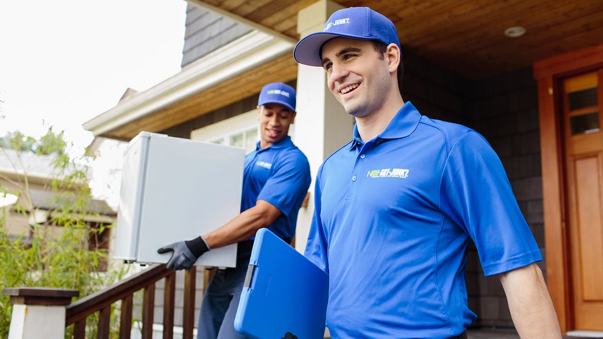 1-800-GOT-JUNK? truck team members picking up a mini fridge from a customer’s home.