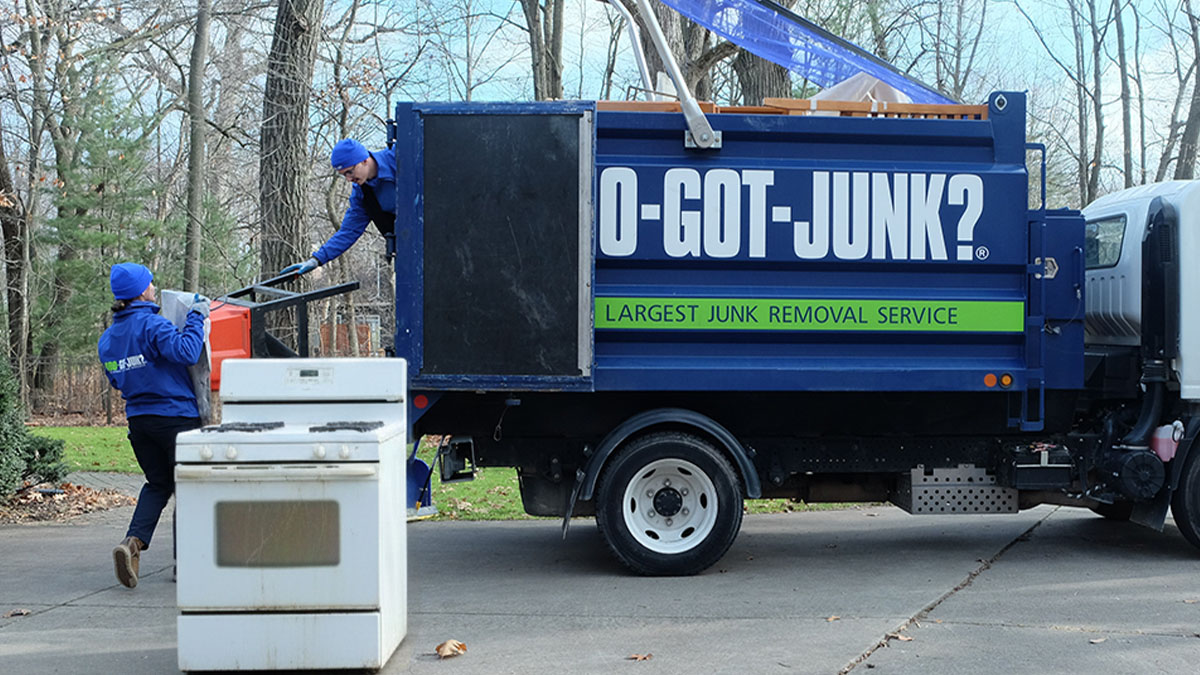 1-800-GOT-JUNK? truck team dropping off old appliances at a recycling center.