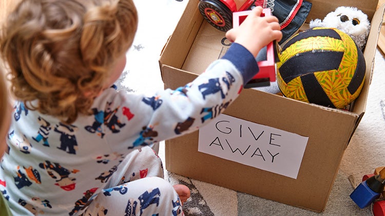 Child putting toys in box for donations
