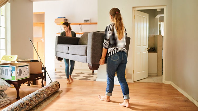Mom and daughter carrying an old couch to get rid of it