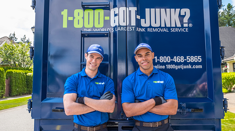 Two 1-800-GOT-JUNK? employees behind junk truck Two 1-800-GOT-JUNK? employees behind junk truck