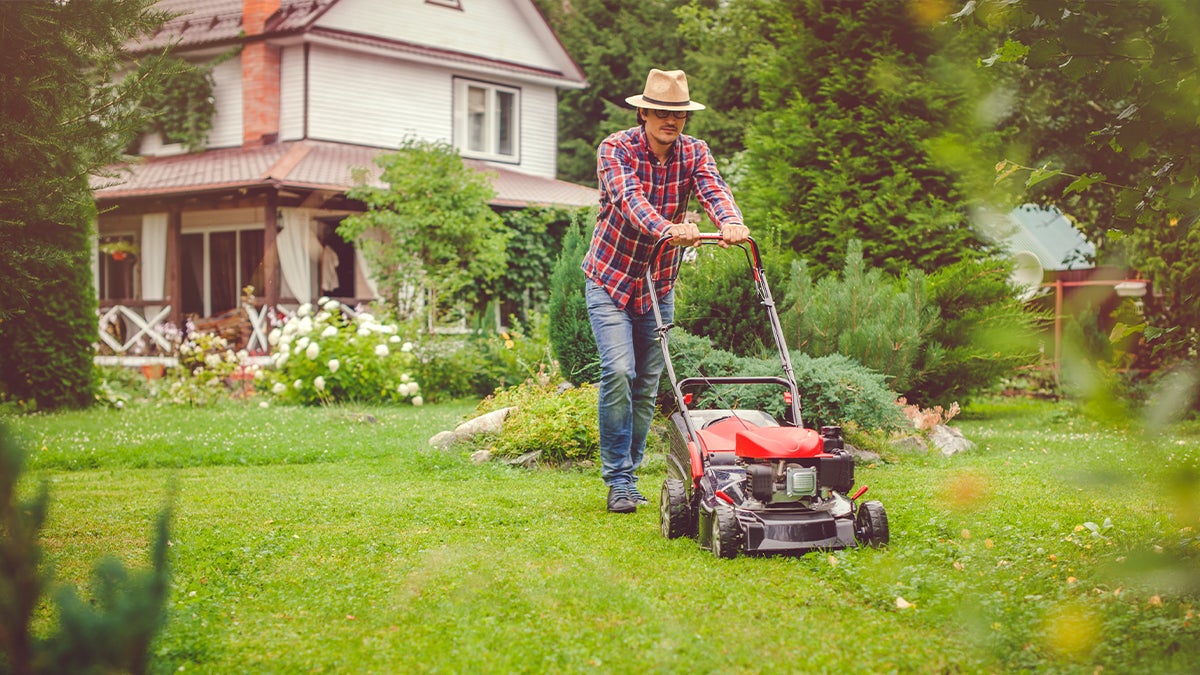 Man mowing the lawn in front of a house