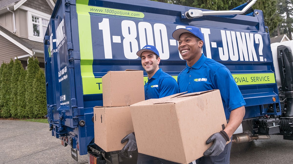 Truck team members carrying a box to dispose of a printer