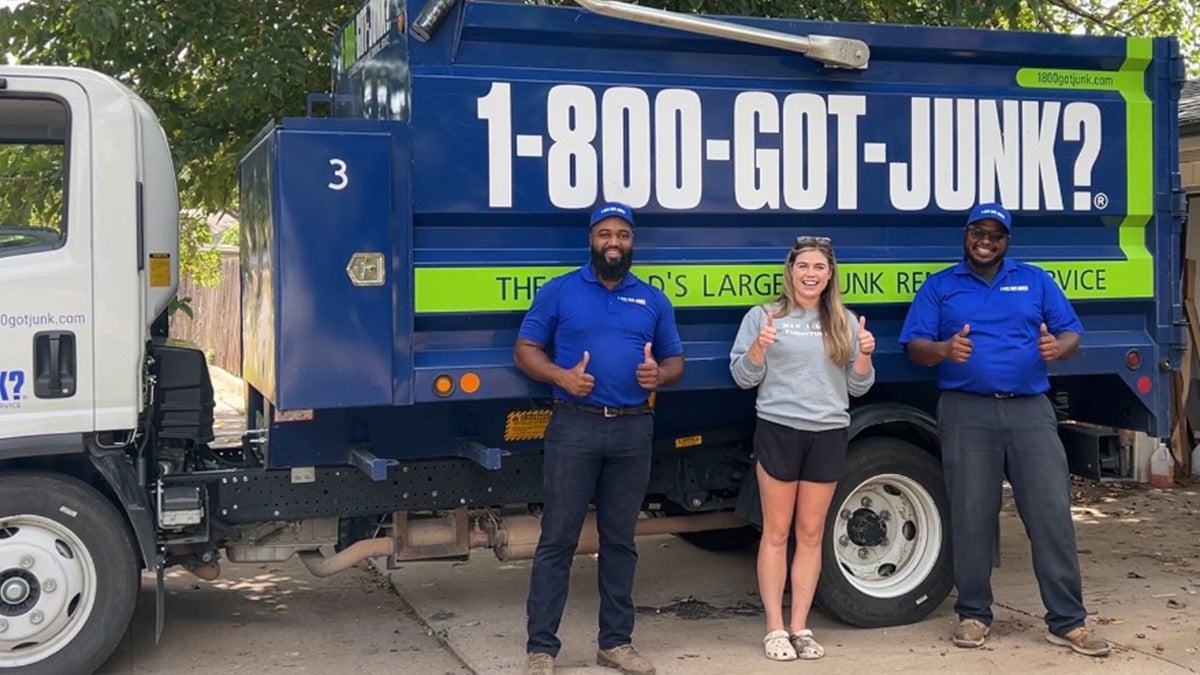 The Durniture Dr and 1-800-GOT-JUNK? team standing beside a 1-800-GOT-JUNK? truck smiling and giving thumbs up