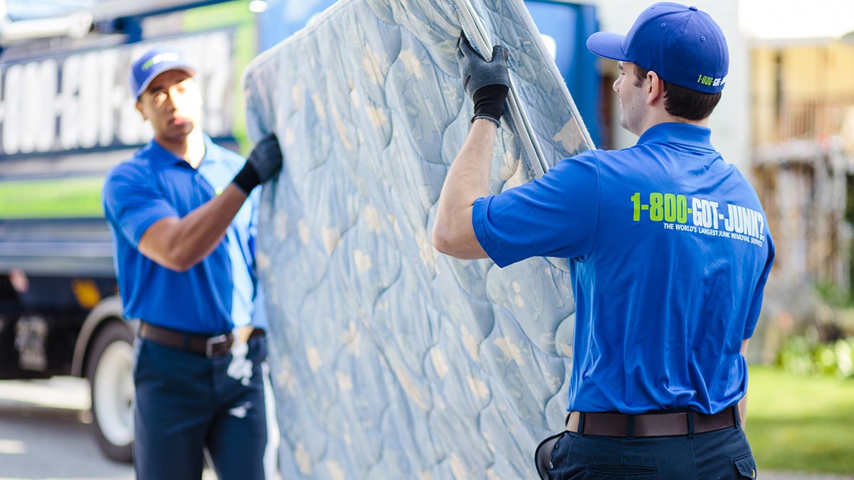 Two 1-800-GOT-JUNK? team members carrying a mattress