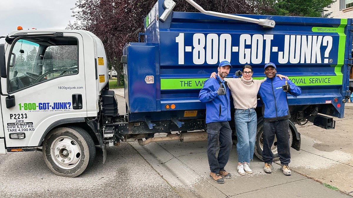 Parked 1-800-GOT-JUNK? Truck with three people standing beside it. Two of them are employees of the company, one of them is Megan Golightly from Go Simplified