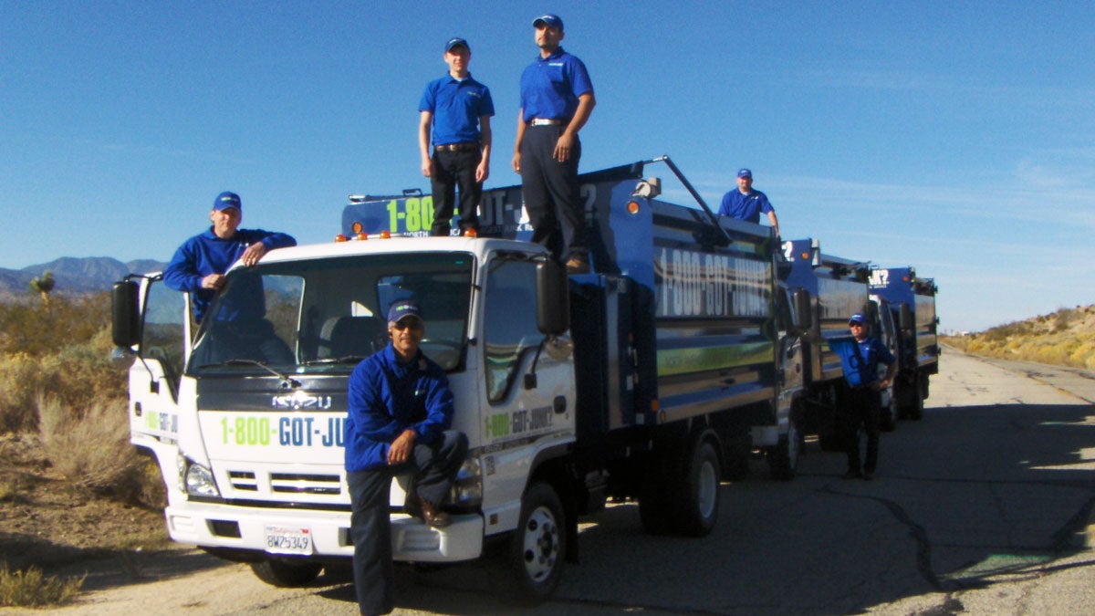 1-800-GOT-JUNK? crew standing in and around 3 junk trucks