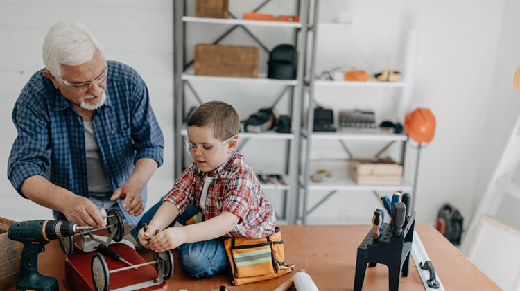 Grandfather and grandson fixing a wagon on a workbench 