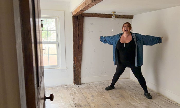 A woman happily standing in her junk-free bedroom.