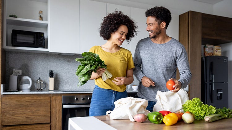 Couple sorting their vegetable groceries on the kitchen counter Couple sorting their vegetable groceries on the kitchen counter