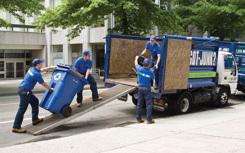 Four 1-800-GOT-JUNK? team members loading commercial junk into a 1-800-GOT-JUNK? truck