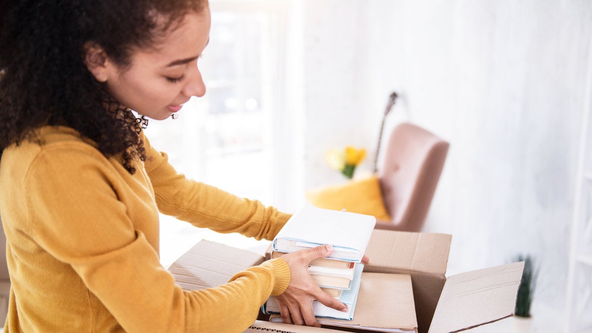 Women in a house putting books in a box