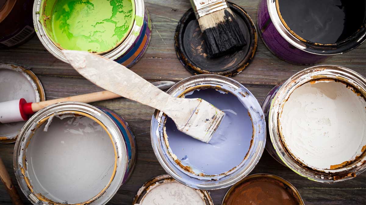 Multiple hazardous open paint cans of varying color