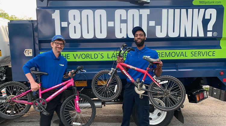 Two 1-800-GOT-JUNK? team members holding bikes