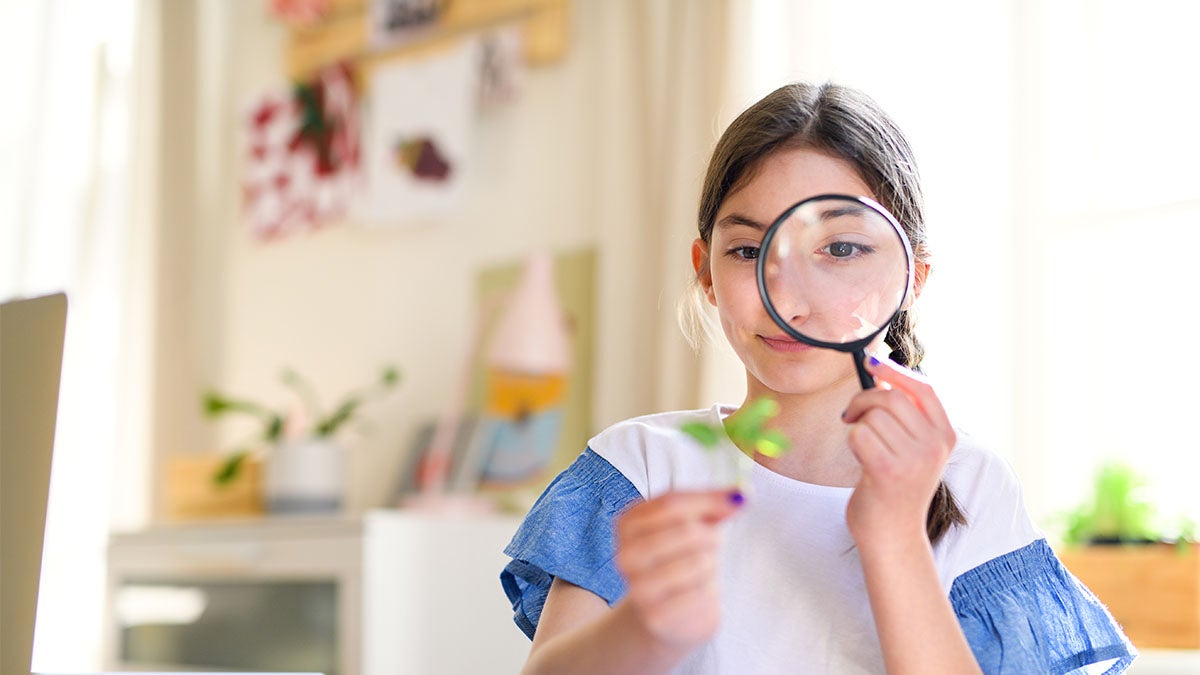 Student studying a plant with a magnifying glass