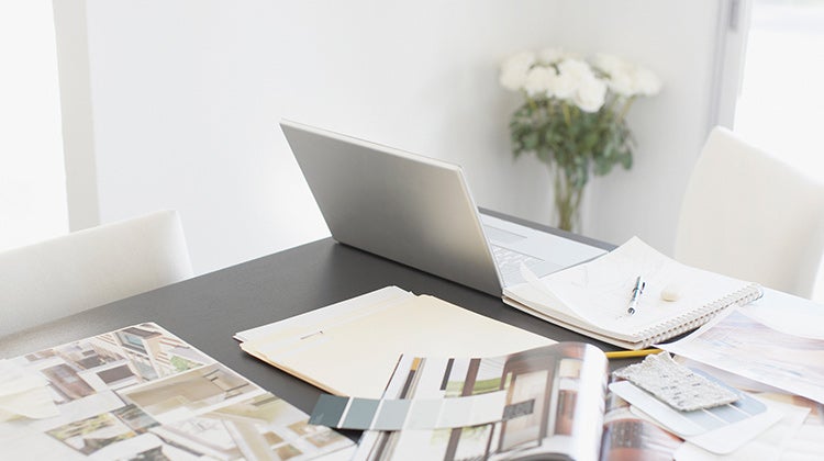 Laptop and design magazines spread out on a table