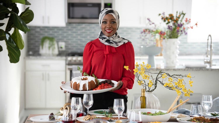 Saudah Saleem holding a serving tray at a table Saudah Saleem holding a serving tray at a table