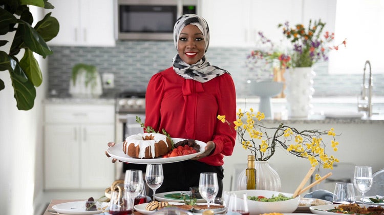 Saudah Saleem holding a serving tray at a table 