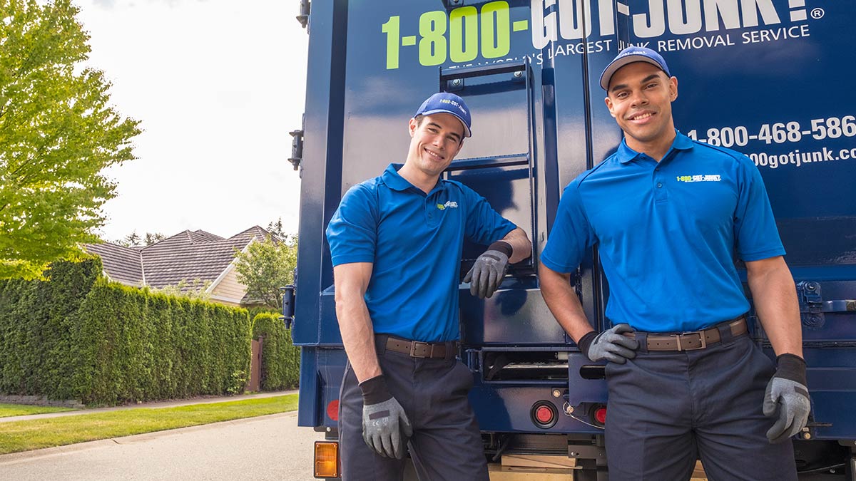 Two TOMs smiling in front of a 1-800-GOT-JUNK? truck