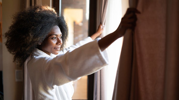Woman in a robe looking out a hotel window