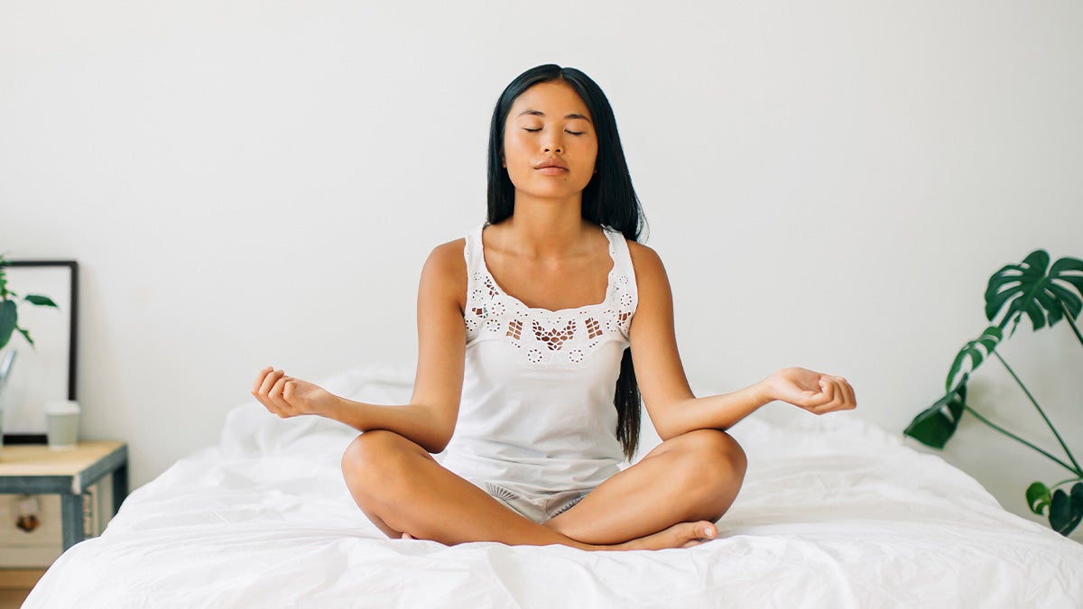 Woman meditating on a bed