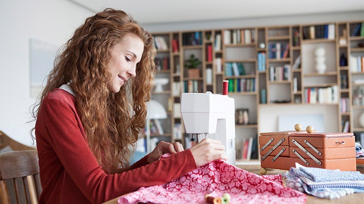 Woman with curly red hair using a sewing machine