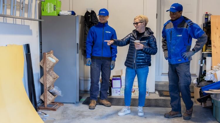 A customer in their garage, pointing out some junk to two 1-800-GOT-JUNK team members. 