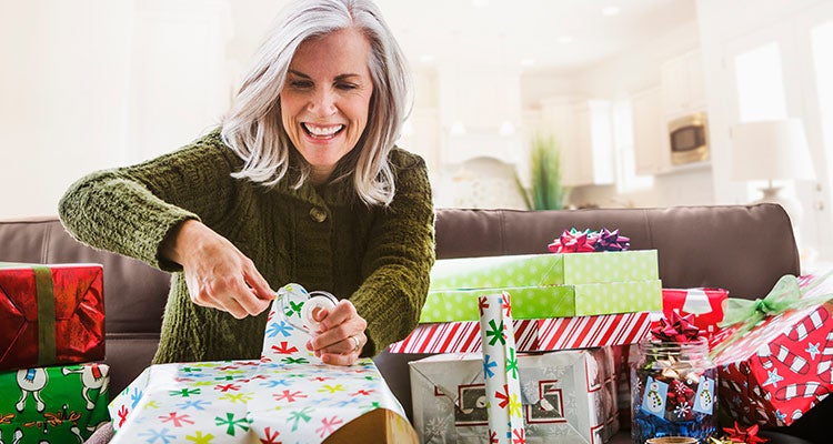 Woman happily wrapping holiday presents Woman happily wrapping holiday presents