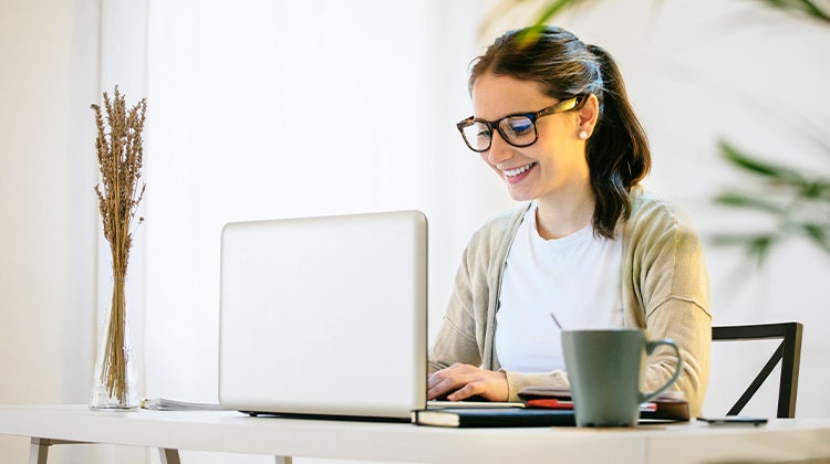 Woman smiling and working on laptop Woman smiling and working on laptop