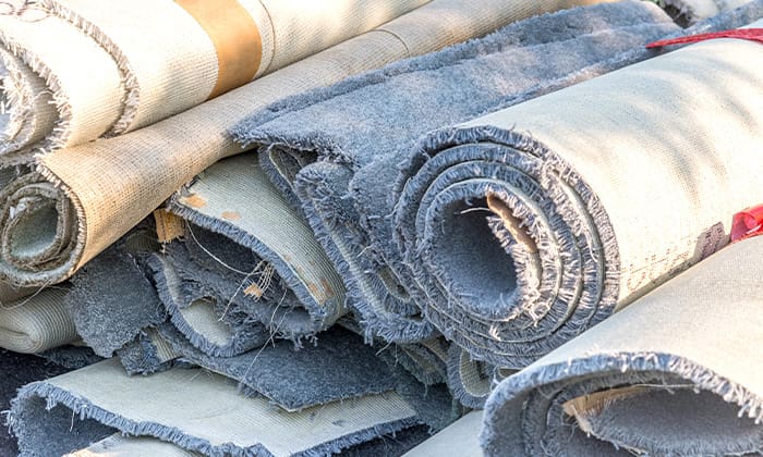 How to remove carpet like a pro Stack of old rolls of carpet under natural lighting